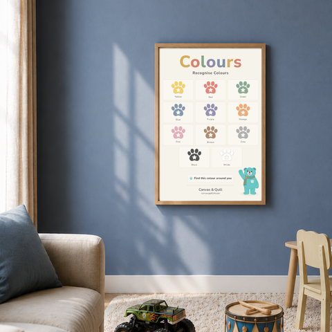 Close-up of the Landing Ready® Colours Wall Chart showing colour recognition activities. A framed children's educational poster titled 'Colours' hanging on a blue wall in a styled child's room. The poster shows 11 different colored paw prints labeled with color names, plus a small blue teddy bear at the bottom right.